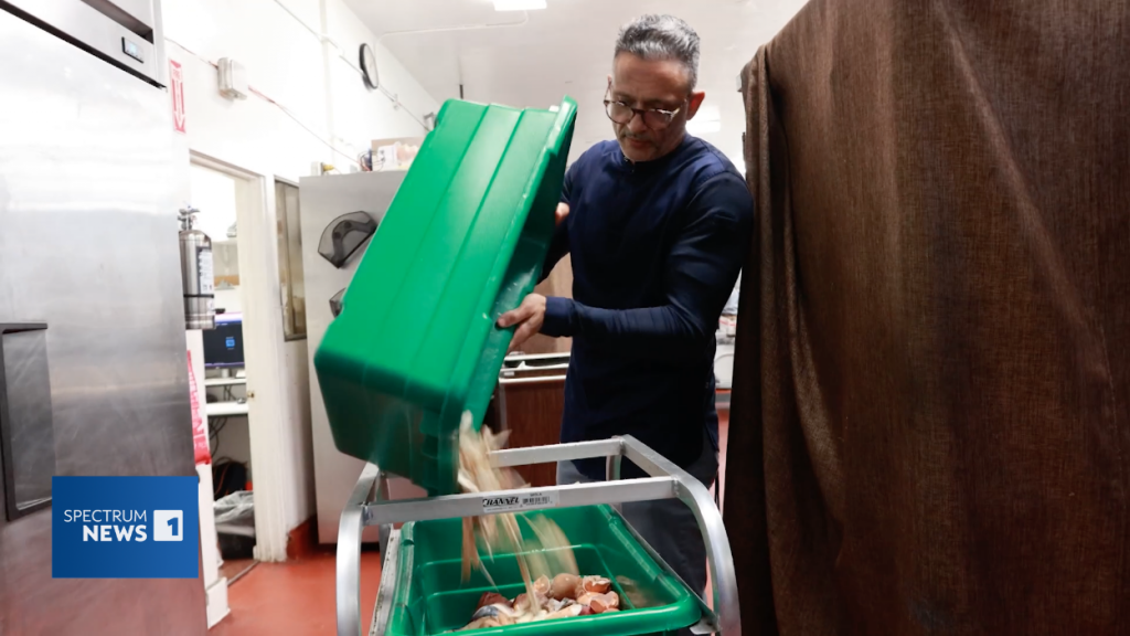 The head chef at the Fairmont Miramar hotel adds organic waste to a green plastic bin, that will be added to the hotel's on-site composting machine.